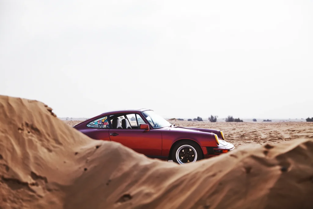 Wine-red 1982 Porsche 911 SC in urban and desert settings in Dubai.