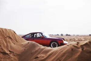 Wine-red 1982 Porsche 911 SC in urban and desert settings in Dubai.