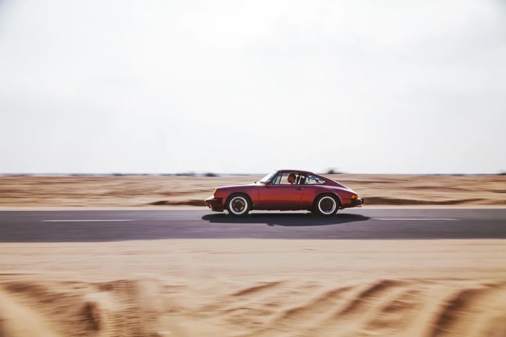 Wine-red 1982 Porsche 911 SC in urban and desert settings in Dubai.