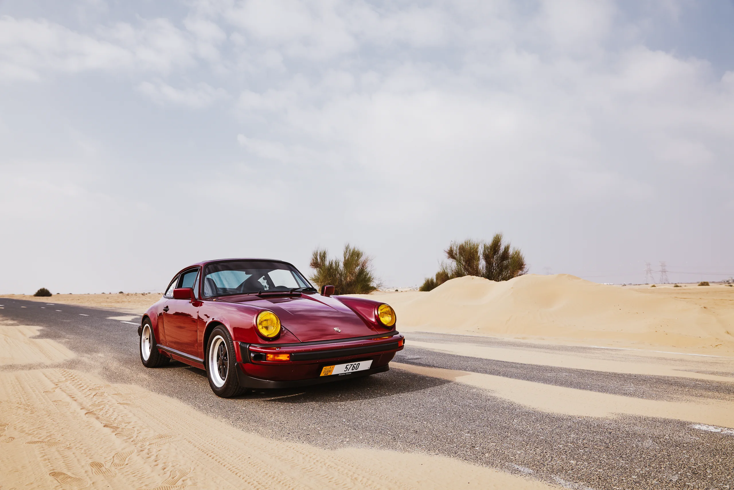 Wine-red 1982 Porsche 911 SC in urban and desert settings in Dubai.
