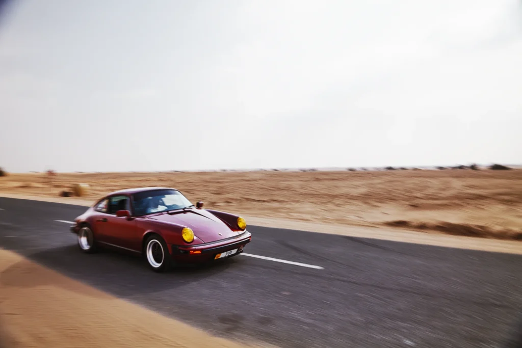 Wine-red 1982 Porsche 911 SC in urban and desert settings in Dubai.