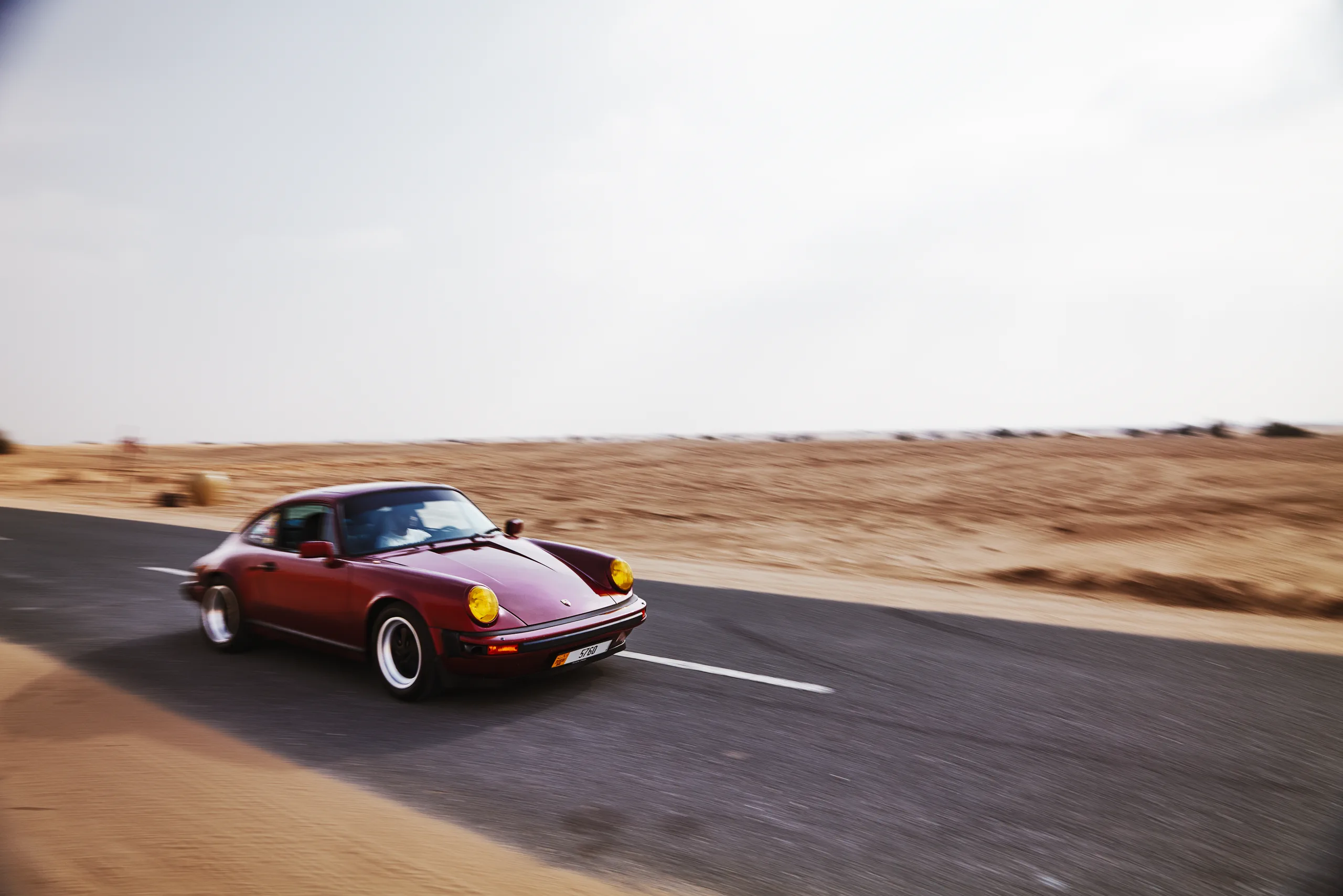 Wine-red 1982 Porsche 911 SC in urban and desert settings in Dubai.