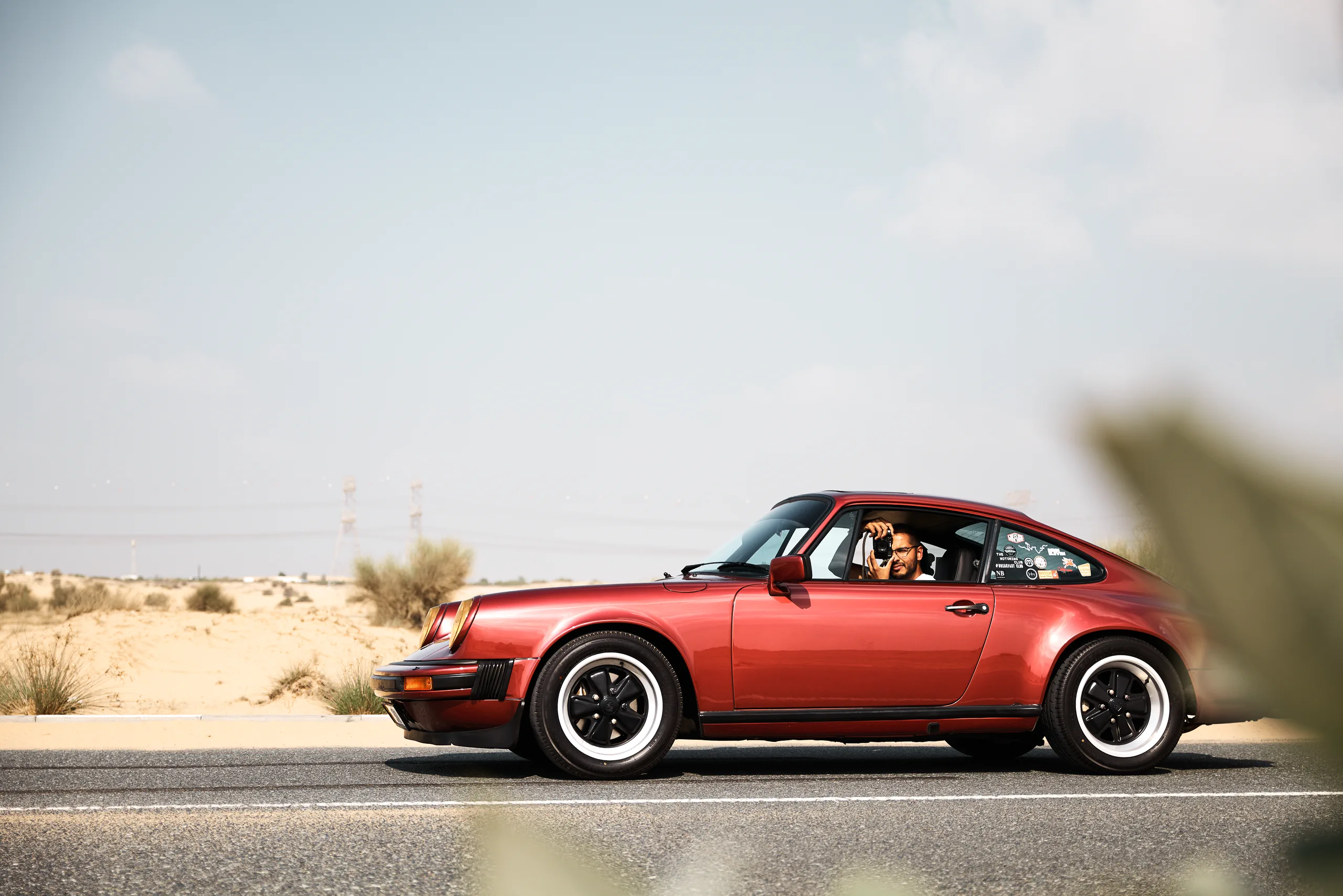 Wine-red 1982 Porsche 911 SC in urban and desert settings in Dubai.