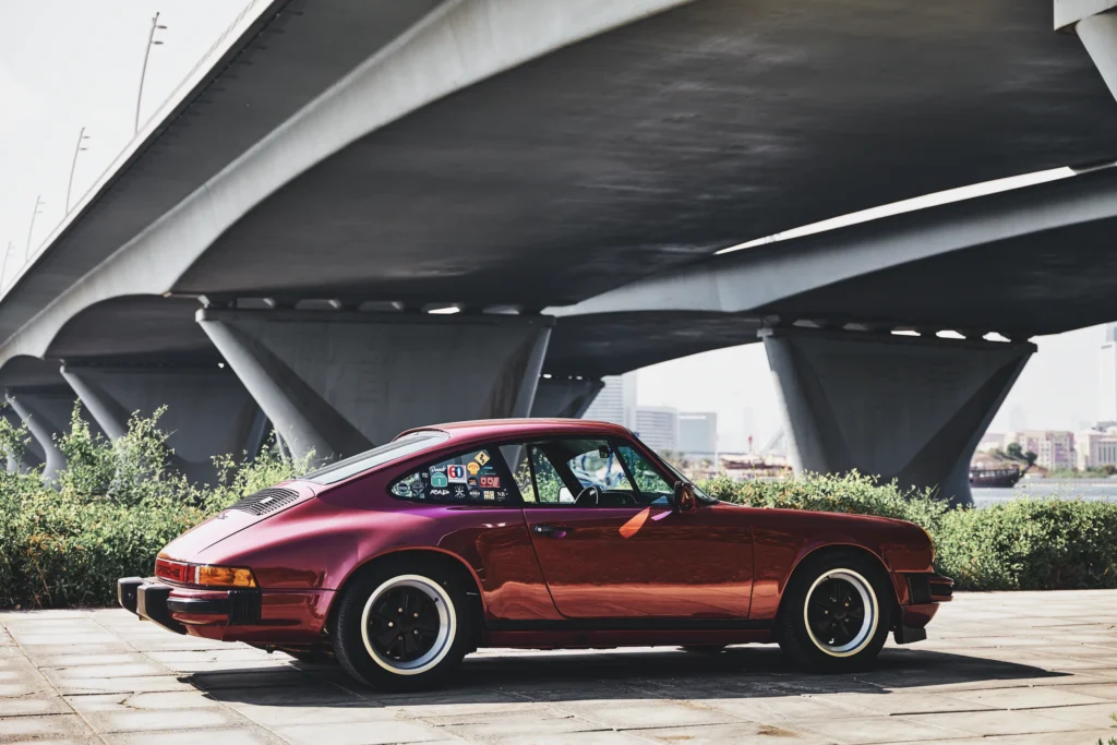 Wine-red 1982 Porsche 911 SC in urban and desert settings in Dubai.