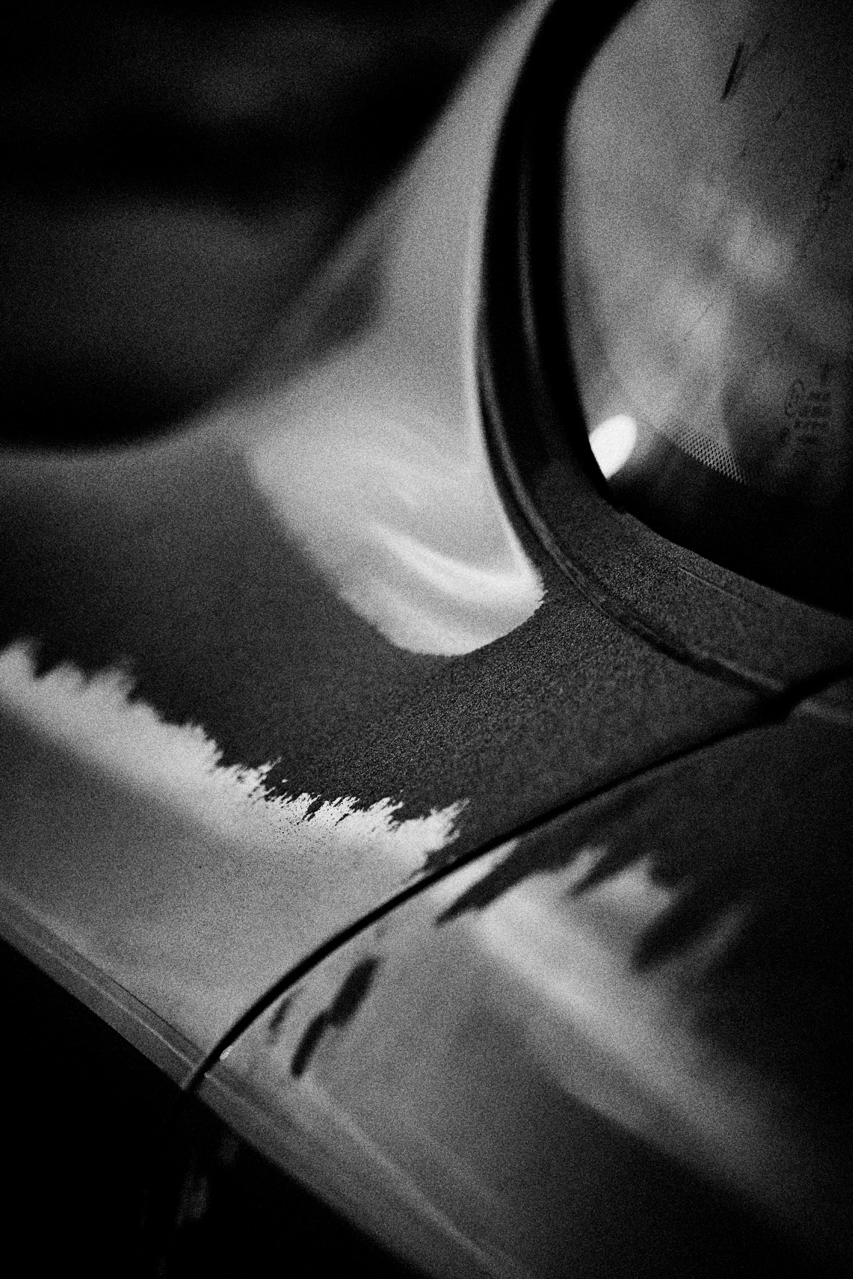 Grainy black-and-white panning photograph of an off-road Porsche Cayman driving along a desert road.