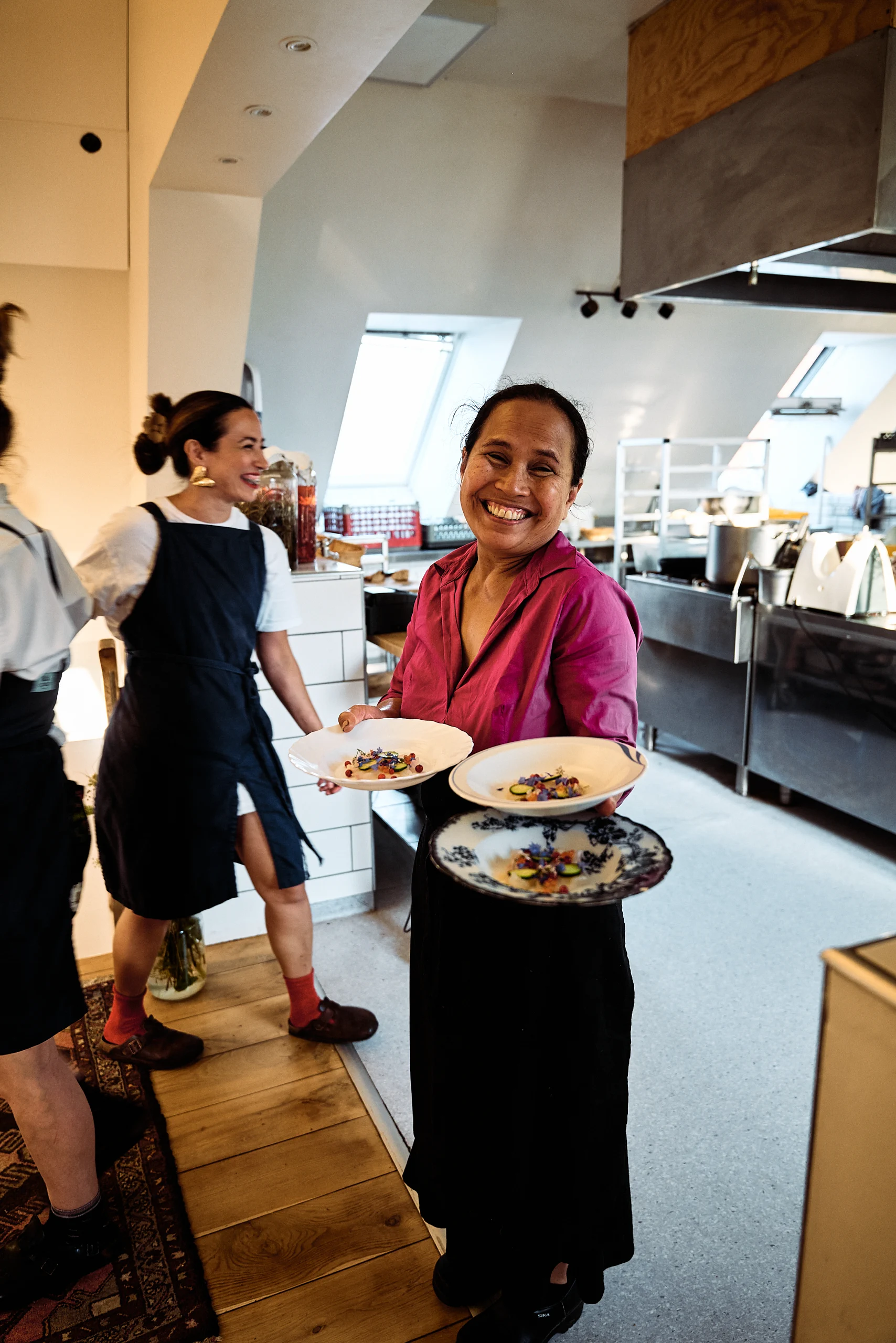 Chefs carrying freshly prepared dishes through the kitchen