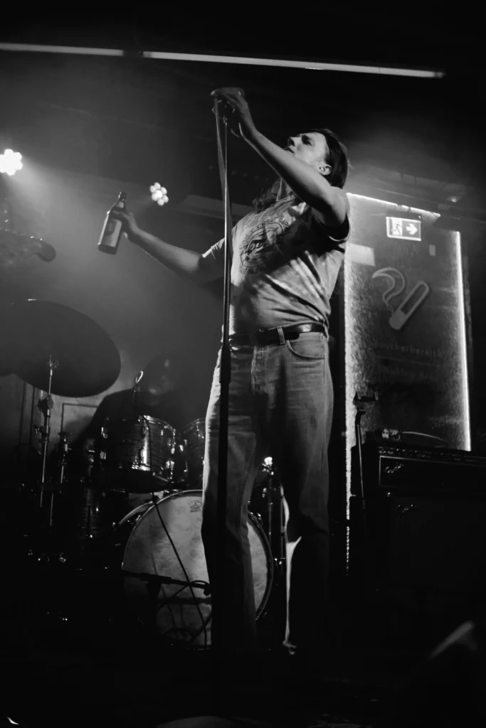 The vocalist of REAL FARMER raising a microphone during a live performance in Cologne.