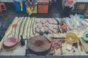 Assorted animal products arranged around a worn chopping block at a Malaysian wet-market stall.