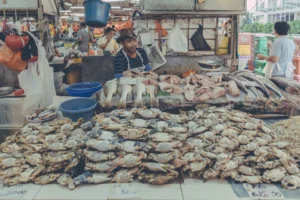 Fish and shellfish piled across a busy seafood counter at a wet market in Malaysia.