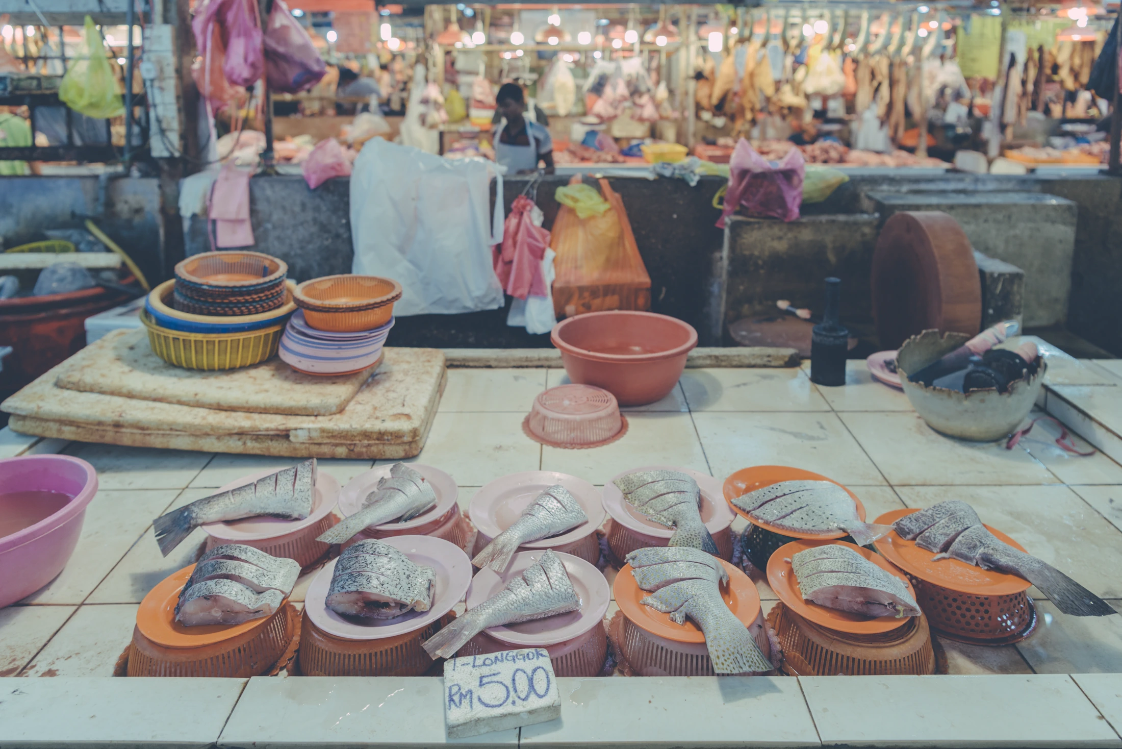 Ceramic bowls containing seafood products arranged across a market counter in Malaysia.