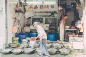 Fish vendor working among rows of metal basins outside a traditional wet-market shop in Hong Kong.
