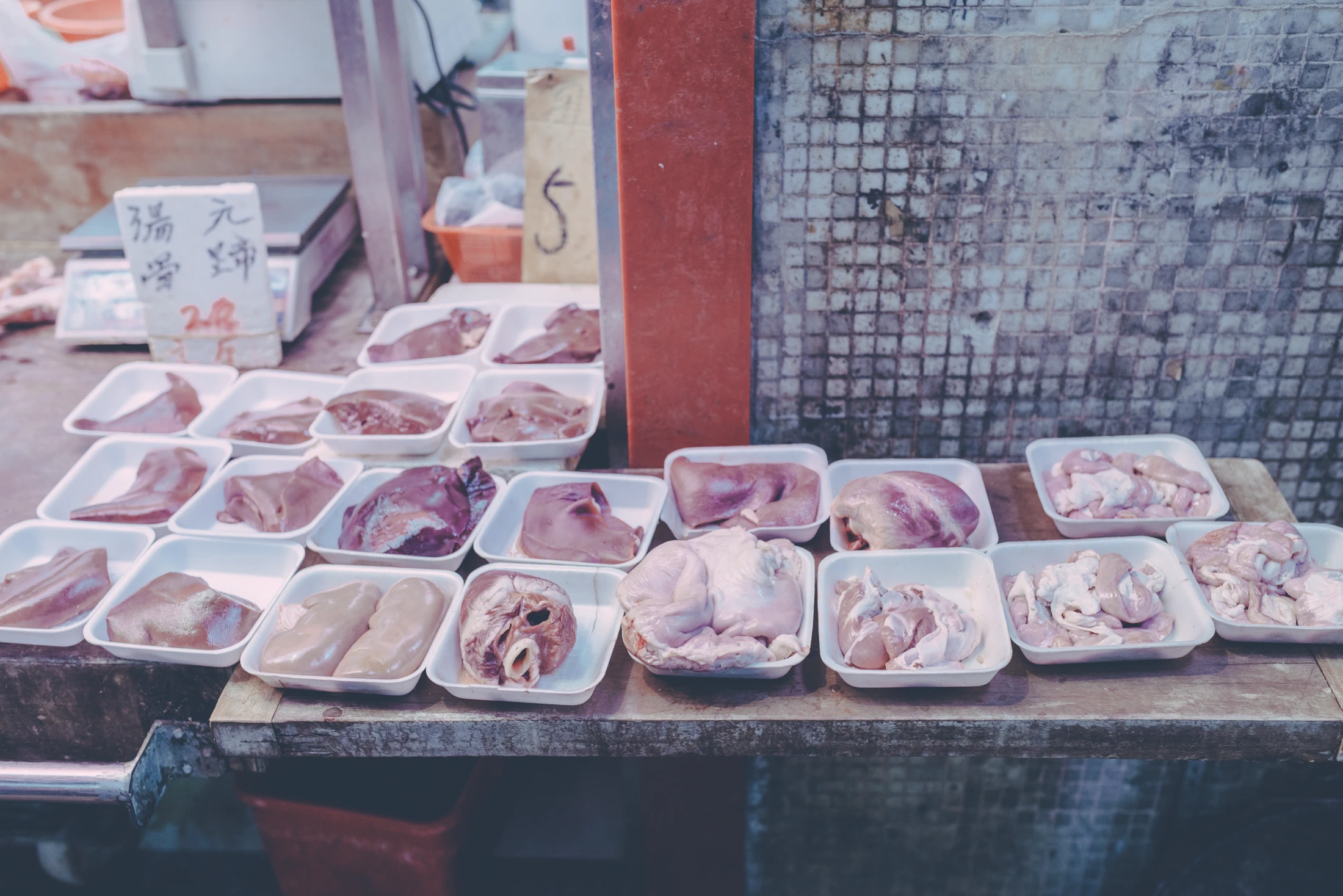 Assorted cuts of raw meat displayed in trays on the counter of a Hong Kong wet-market stall.