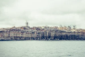 Pale multilayer photograph of Istanbul’s waterfront across the water, with overlapping historic buildings and the Galata Tower emerging through a hazy skyline.