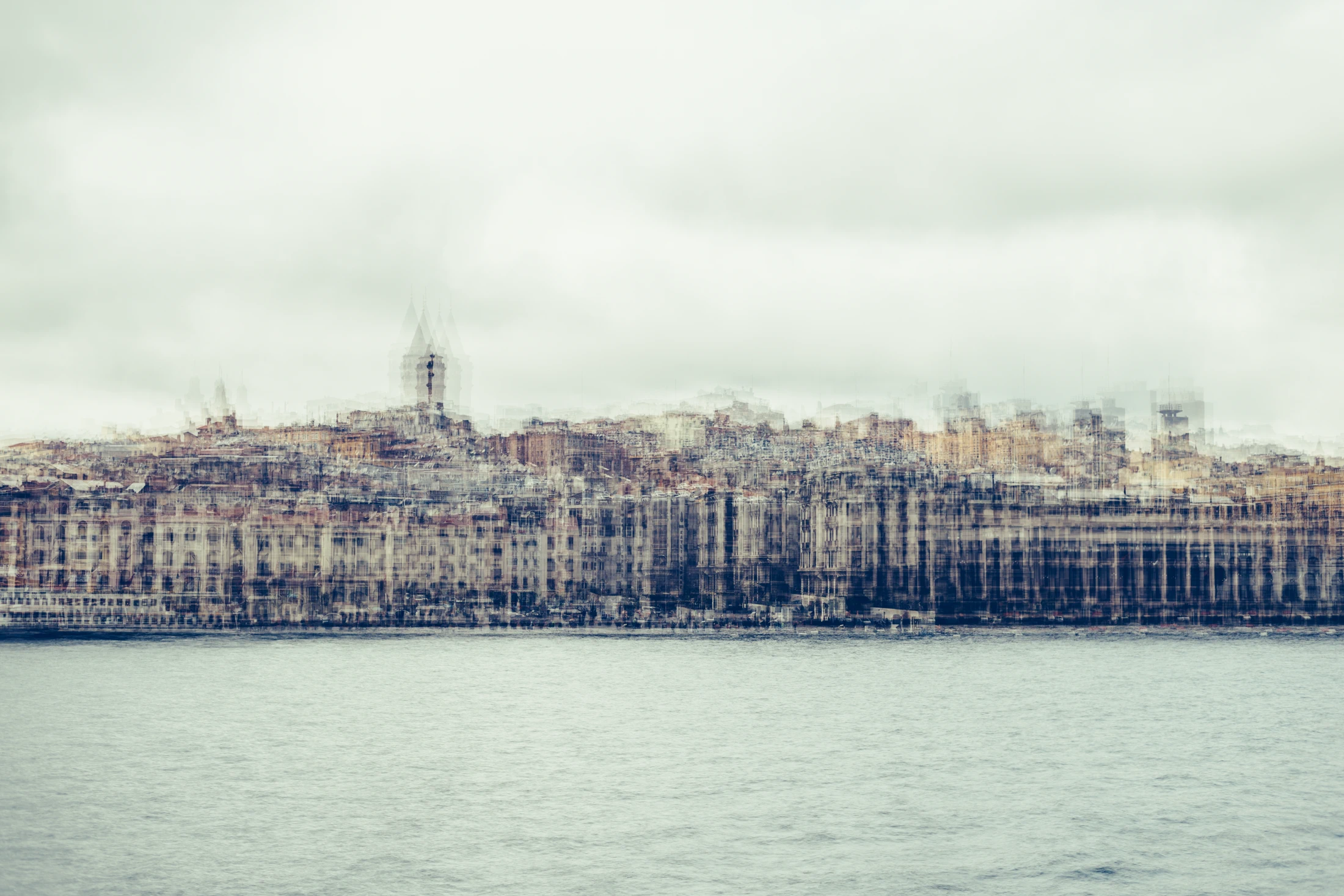 Pale multilayer photograph of Istanbul’s waterfront across the water, with overlapping historic buildings and the Galata Tower emerging through a hazy skyline.
