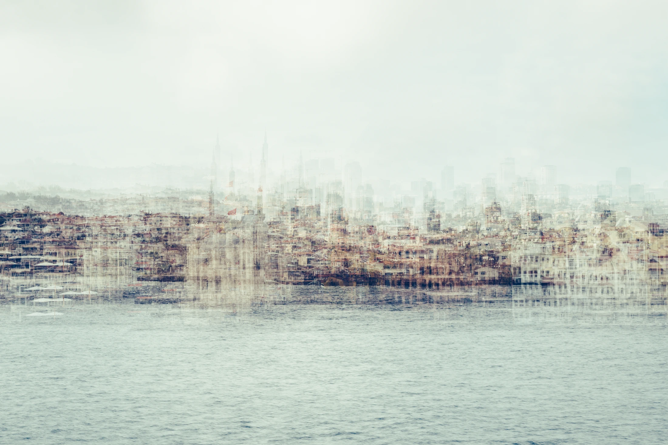 Pale multilayer photograph of Istanbul’s waterfront across the water, with overlapping historic buildings and the Galata Tower emerging through a hazy skyline.