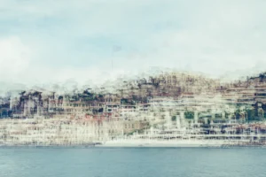 Pale multilayer photograph of Istanbul’s waterfront across the water, with overlapping historic buildings and the Galata Tower emerging through a hazy skyline.